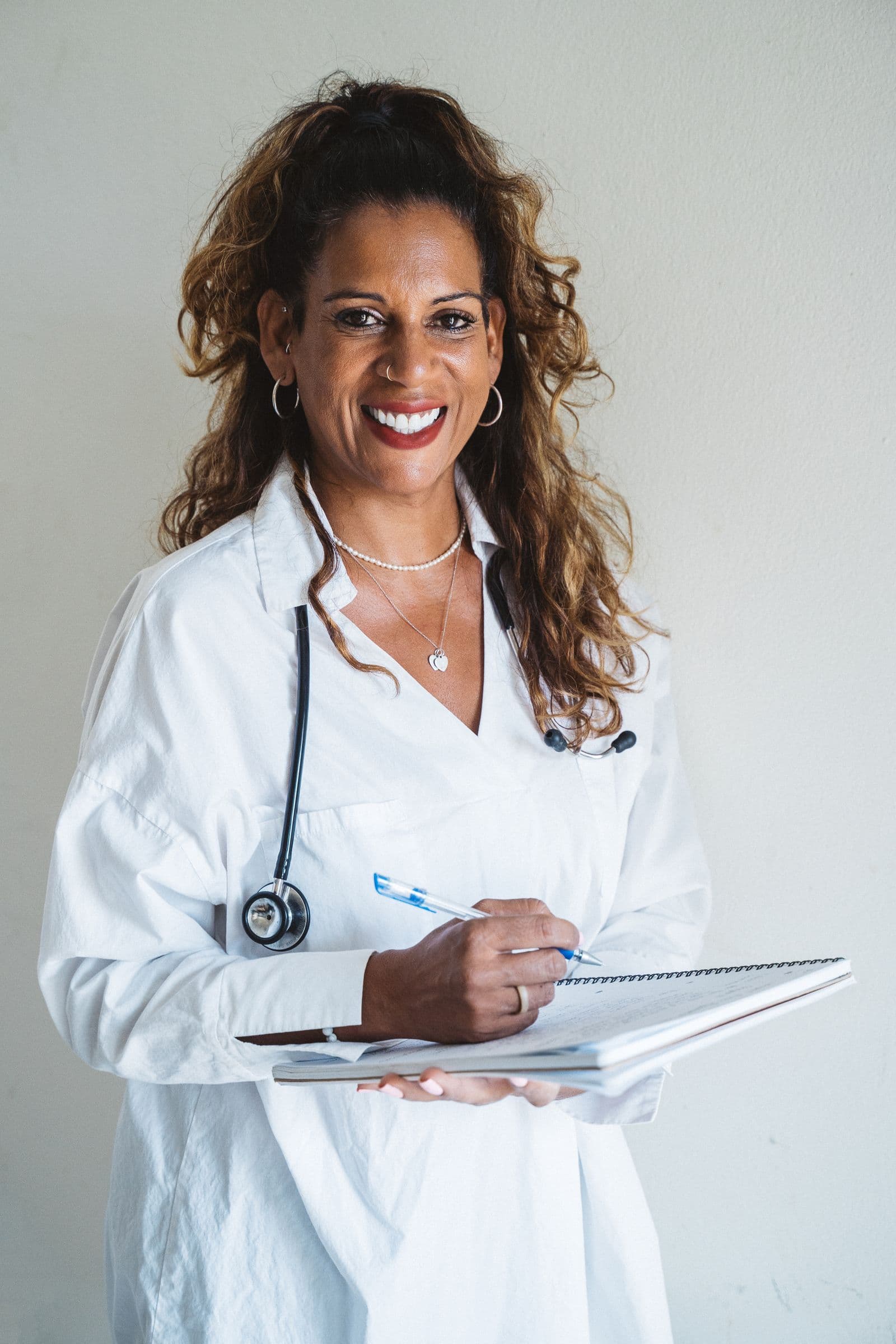 Healthcare professional wearing a white coat and holding a notebook