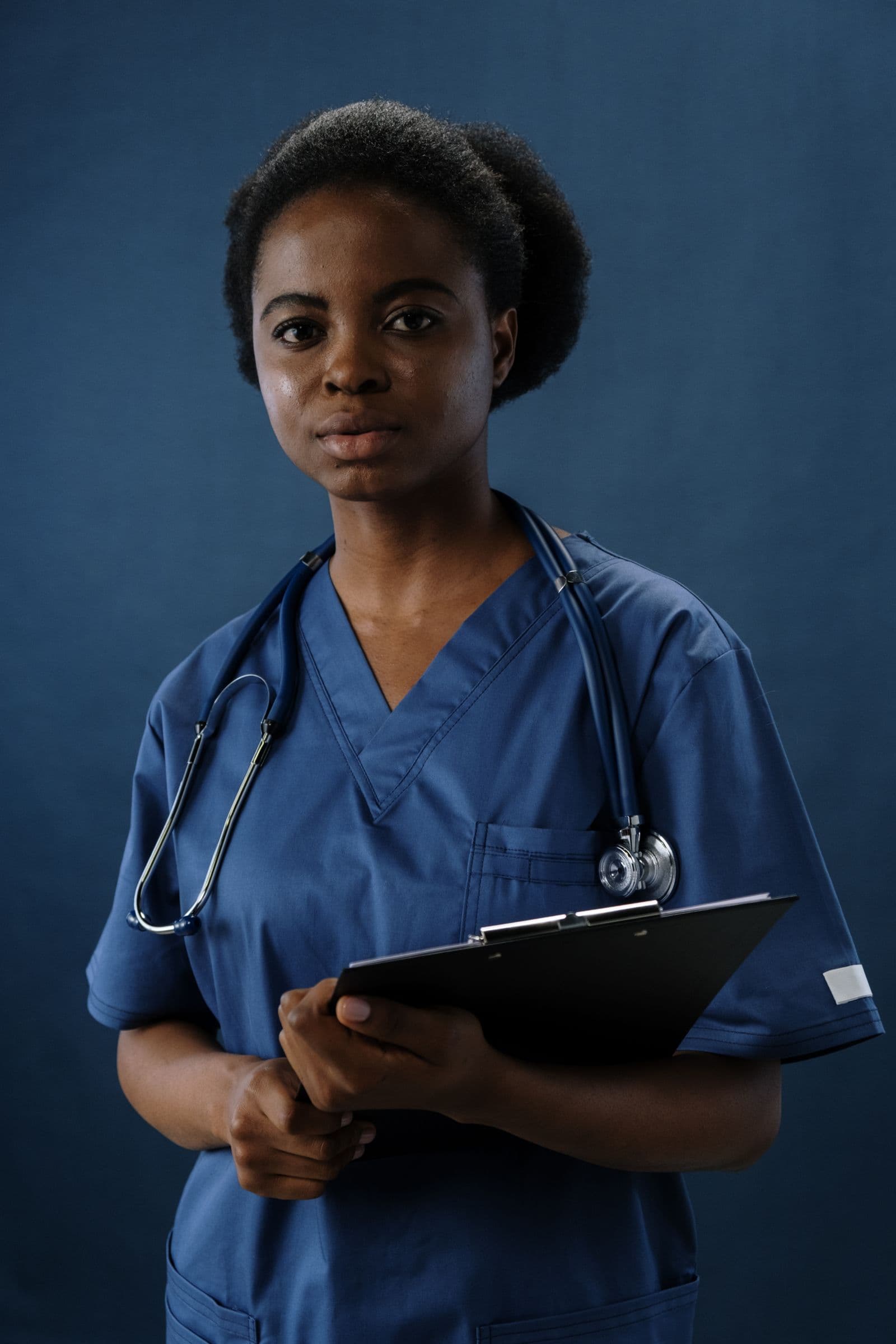 Healthcare professional wearing navy scrubs against a navy background
